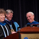 President Emeritus Haas and a faculty member smile while listening to remarks.